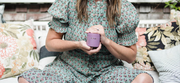 Woman sitting outside holding a glass container of prenatal vitamins - WeNatal for Her